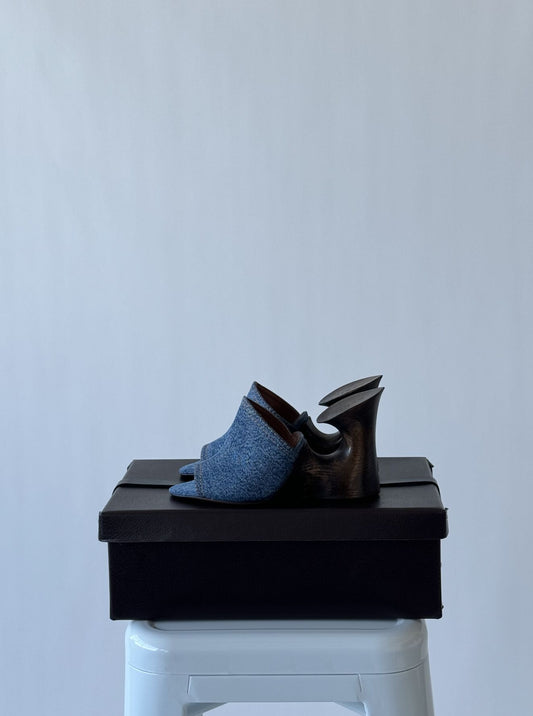 Alaïa La Sculpture Mule Slides by EXCHANGE in blue, size 38, with a unique curved wooden heel. BRAND NEW on original box, RRP $1.8K NZD. Displayed on a white stool against a light gray background.