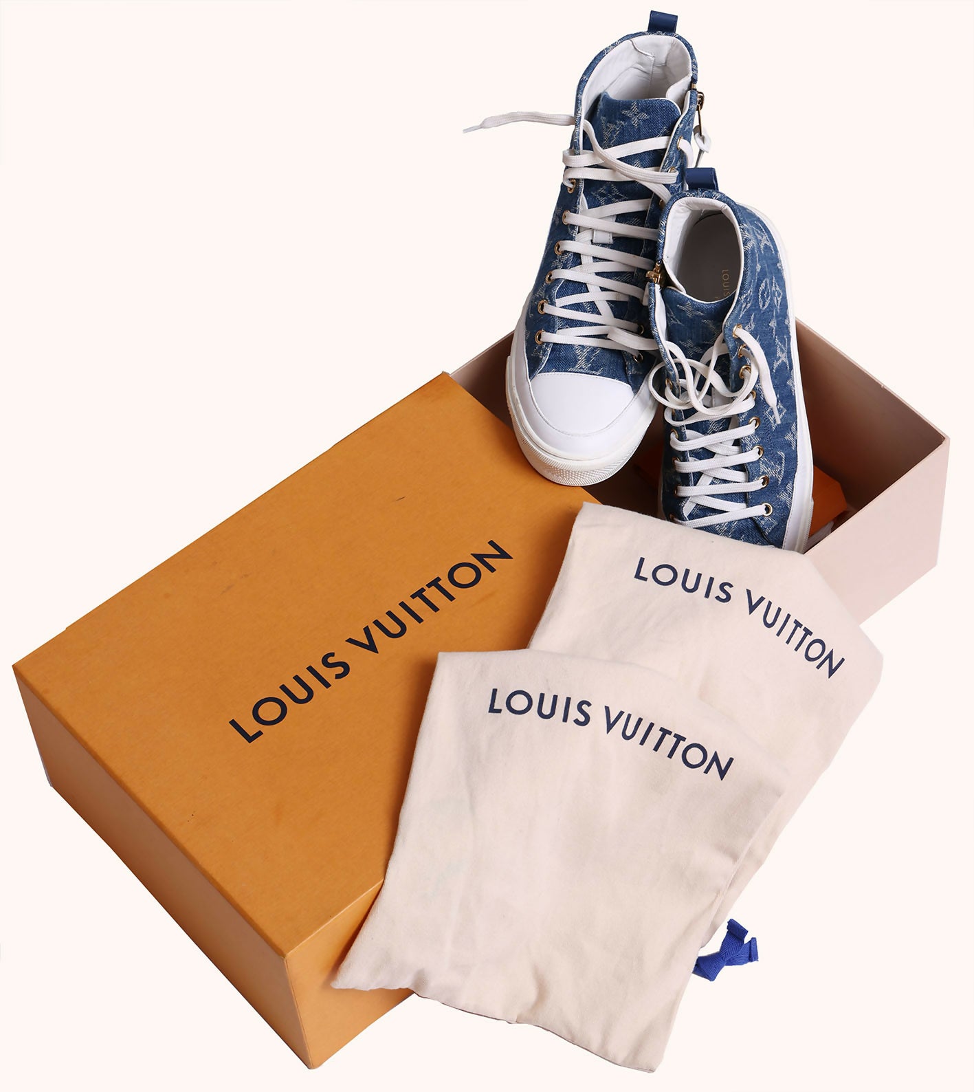 A pair of EXCHANGE Louis Vuitton Sneakers in denim blue monogram are shown next to an open orange box and two white dust bags, all set against a plain background.