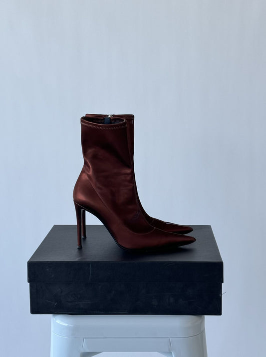 A single Giuseppe Zanotti Ametista 85mm pointed-toe maroon ankle boot in size 39 by EXCHANGE rests on a black Faradays shoebox, placed on a white stool against a plain light gray background.