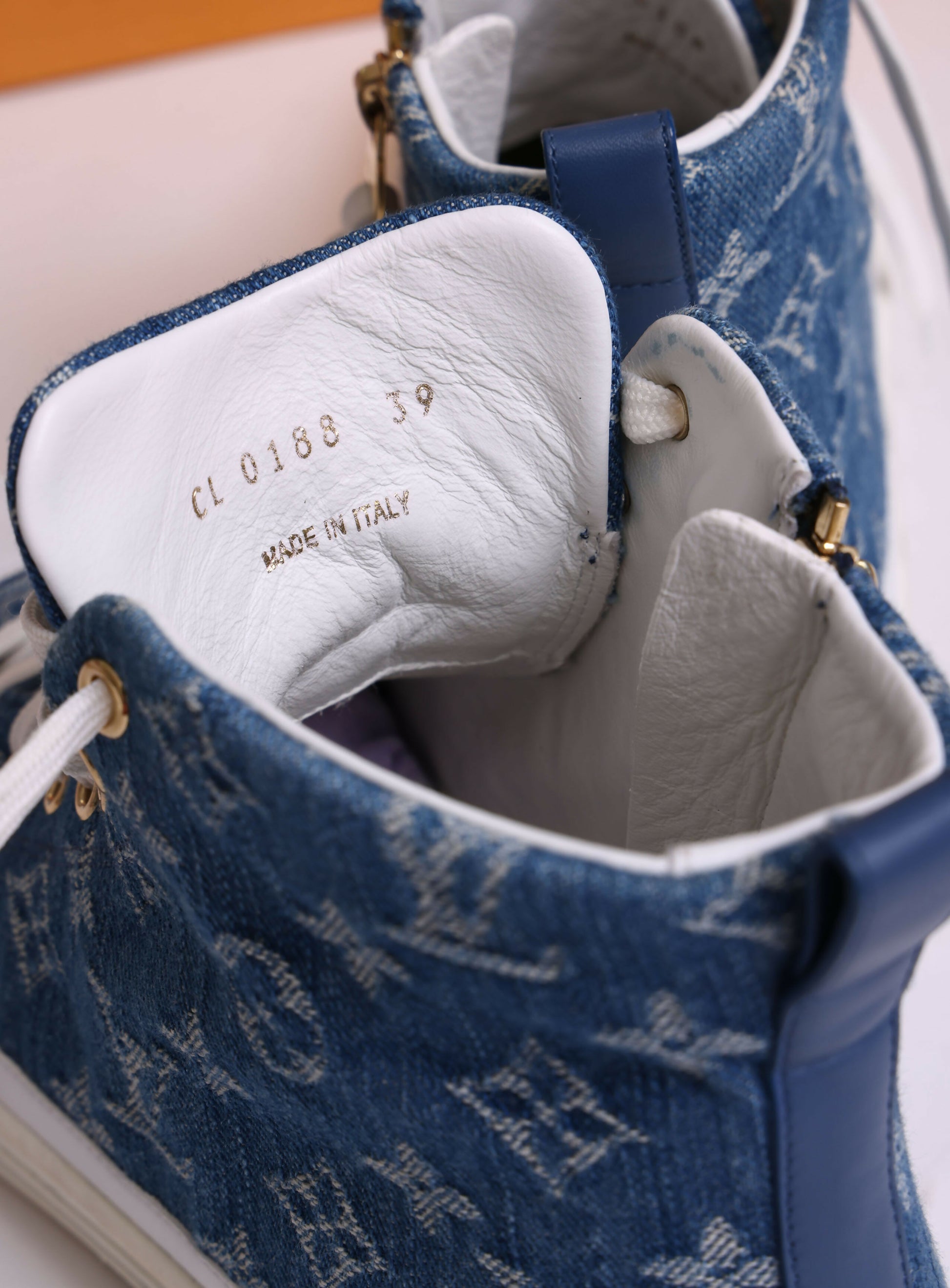 Close-up of the inner tongue of EXCHANGE Louis Vuitton Sneakers in denim blue with white leather lining. Gold text shows CL0188 39 and MADE IN ITALY. Features include white laces, gold eyelets, and a Stellar High Top design.