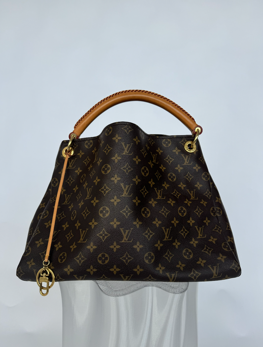 A Louis Vuitton Artsy MM Hobo 2016 by EXCHANGE STORE, in brown monogram canvas with gold hardware and a tan leather handle, is displayed against a plain background, highlighting this elegant preloved designer handbag.