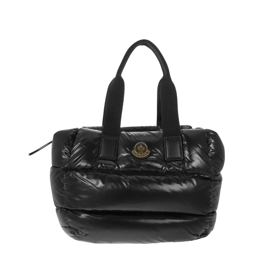 The EXCHANGE Moncler Logo Patch Padded Top Handle Bag features a black padded design, short thick handles, a front circular logo patch, and a zippered top for secure storage.