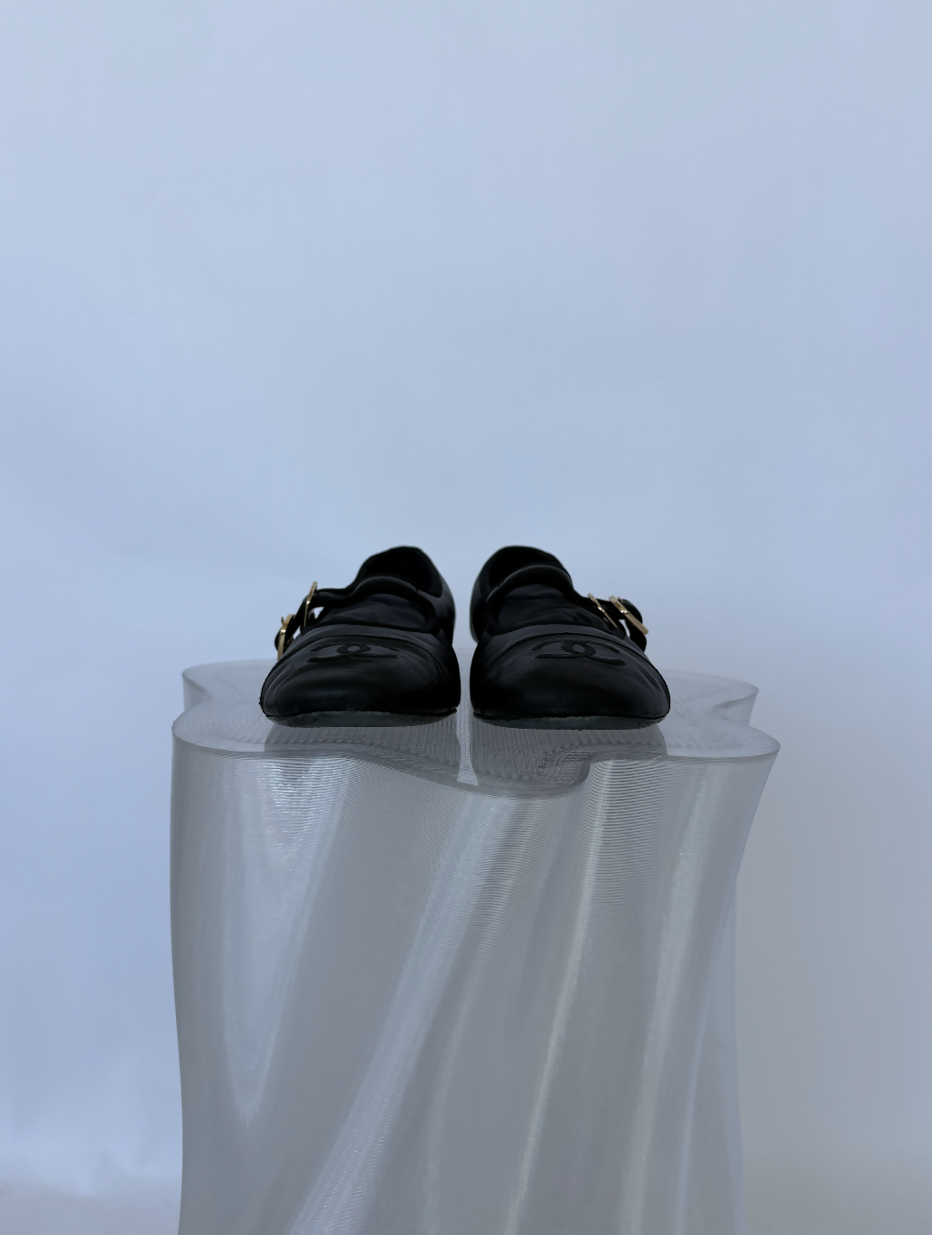 A pair of Chanel Mary Jane flats in Lambskin from EXCHANGE STORE, shown on a wavy-edged translucent pedestal against a light background—a FULL SET that's essential for collectors.
