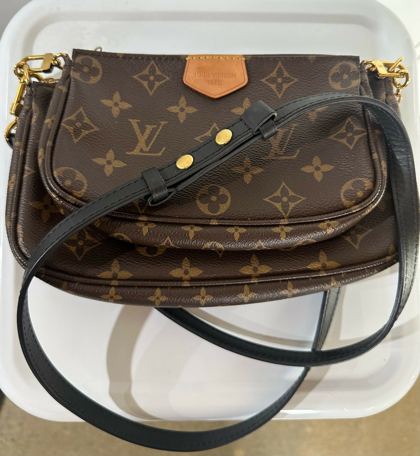 A Louis Vuitton Multi Pochette - Full Set by EXCHANGE is displayed on a white tray.