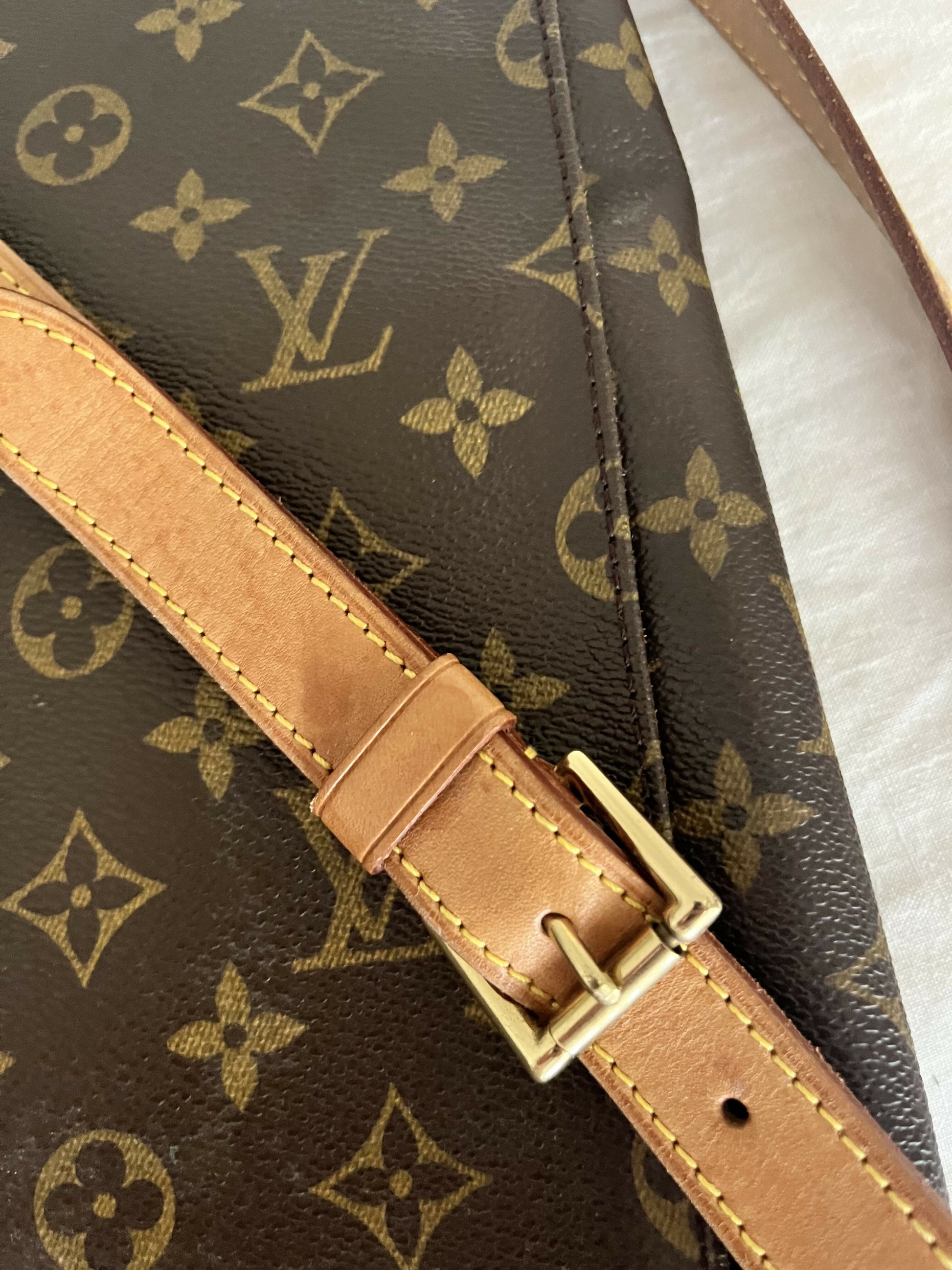 Close-up of an authenticated Louis Vuitton Monogram Musette: brown leather with a tan strap, gold buckle, and iconic logo. Available at EXCHANGE.