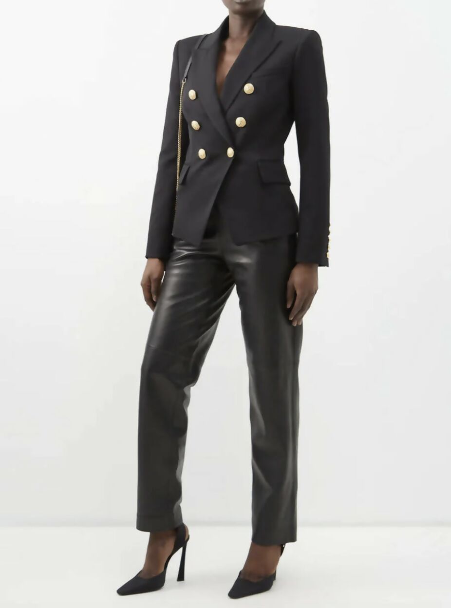 A person in a size 38 EXCHANGE Balmain Blazer Black with gold buttons, black leather pants, and black high-heeled shoes stands against a plain white background.