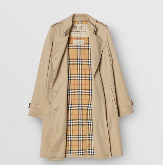 A brand new Burberry Kensington Trench by EXCHANGE hangs open, revealing its iconic check lining in tan, black, white, and red—a timeless cotton gabardine piece with tags.