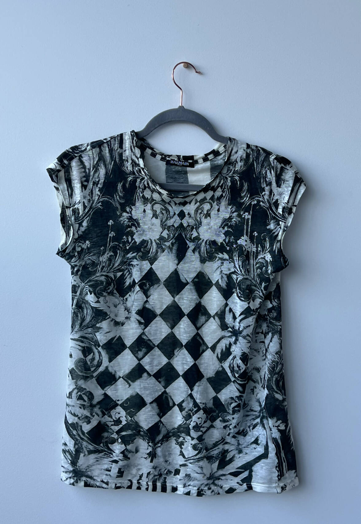 A size 36 EXCHANGE Balmain Printed Tank top with a black and white harlequin diamond and ornate floral pattern is displayed on a hanger against a light gray wall at exchange-store.