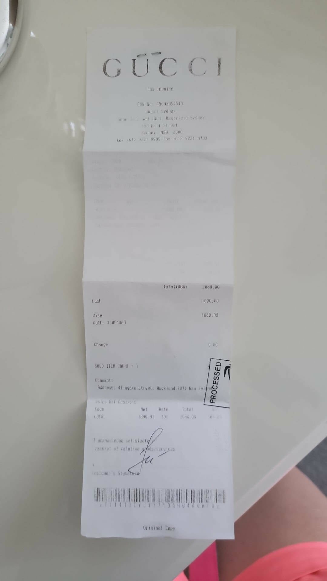 A Gucci marmount small bag receipt from EXCHANGE in excellent condition, with printed and handwritten details showing a $1000.00 total. Purchased May 2018; on a light surface, part of a person in pink shorts is visible.