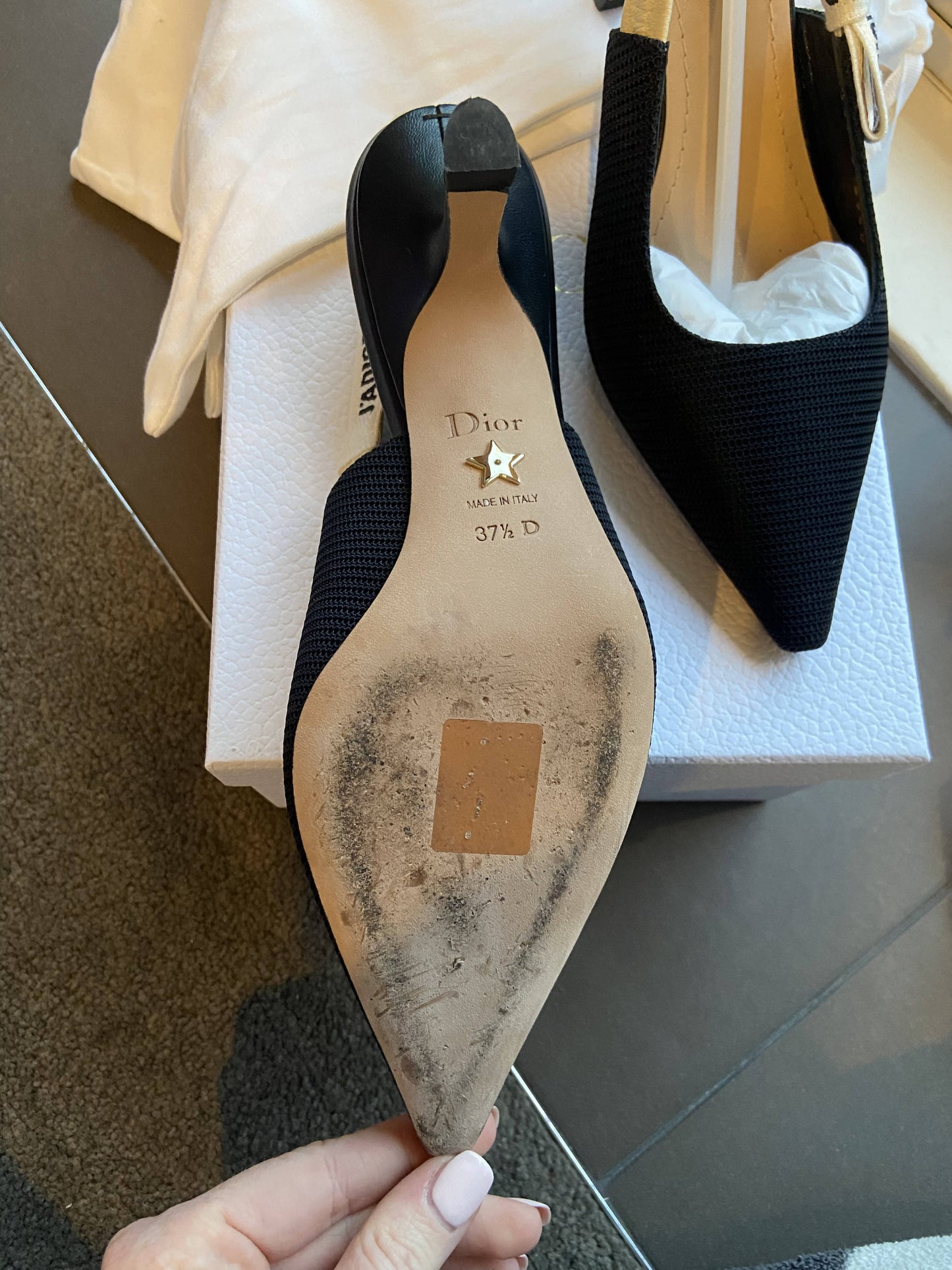 A close-up of EXCHANGE Dior J’adior Slingback heels, size 37.5; one shoe is held to show light sole wear and “Dior Made in Italy” in gold, while both rest elegantly on a white box.