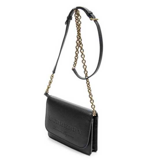 The EXCHANGE Burberry Logo Embossed Wallet On Chain features black grained leather, gold hardware, a gold-tone chain and adjustable strap, and an embossed logo on the front flap, shown on a white background.