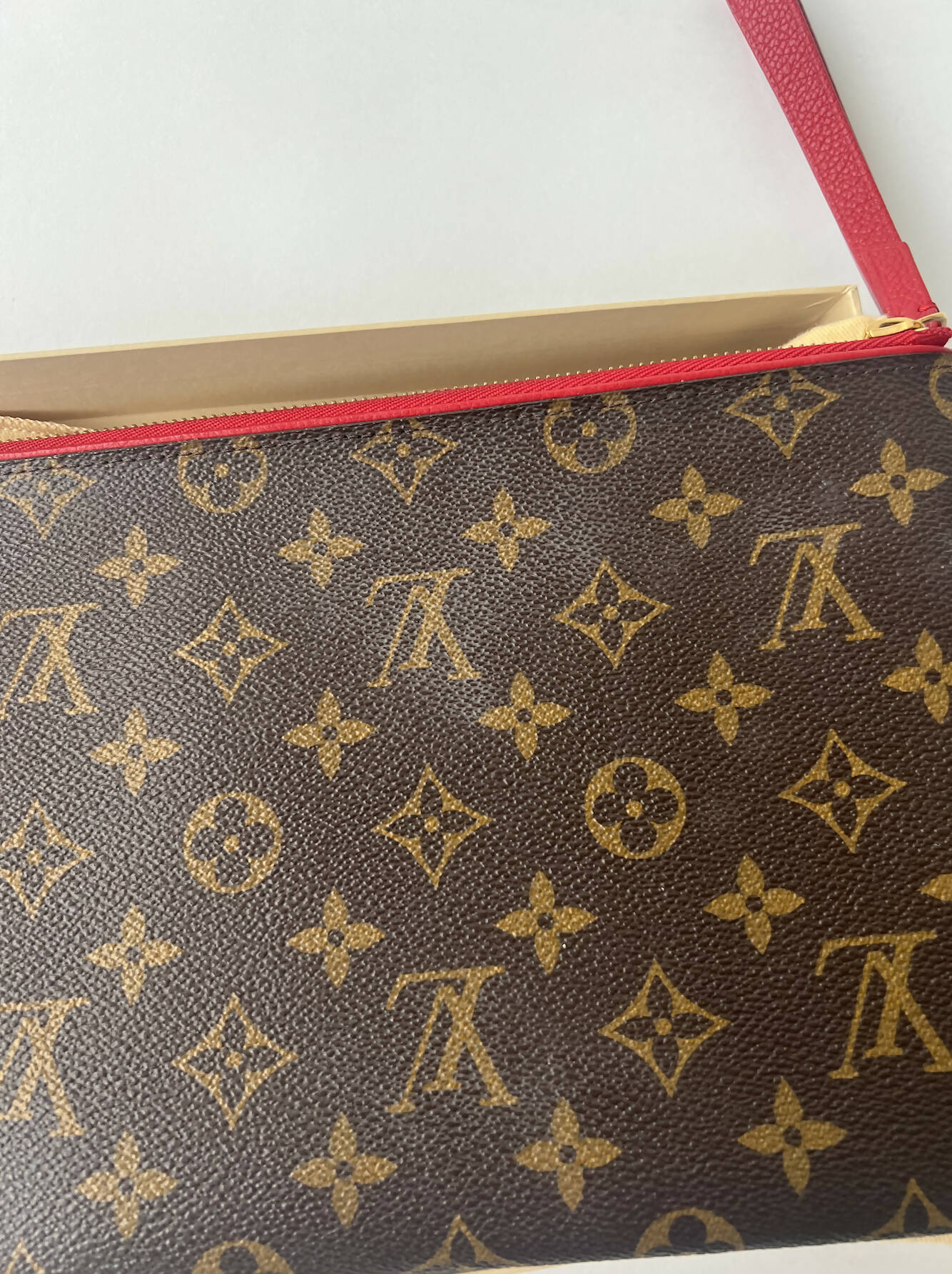 Close-up of a Louis Vuitton Bicolor Monogram Pallas Pochette by EXCHANGE, featuring the signature monogram pattern and red zipper pull, partially inside a beige box on a white surface—box, dustbag, and receipts included.