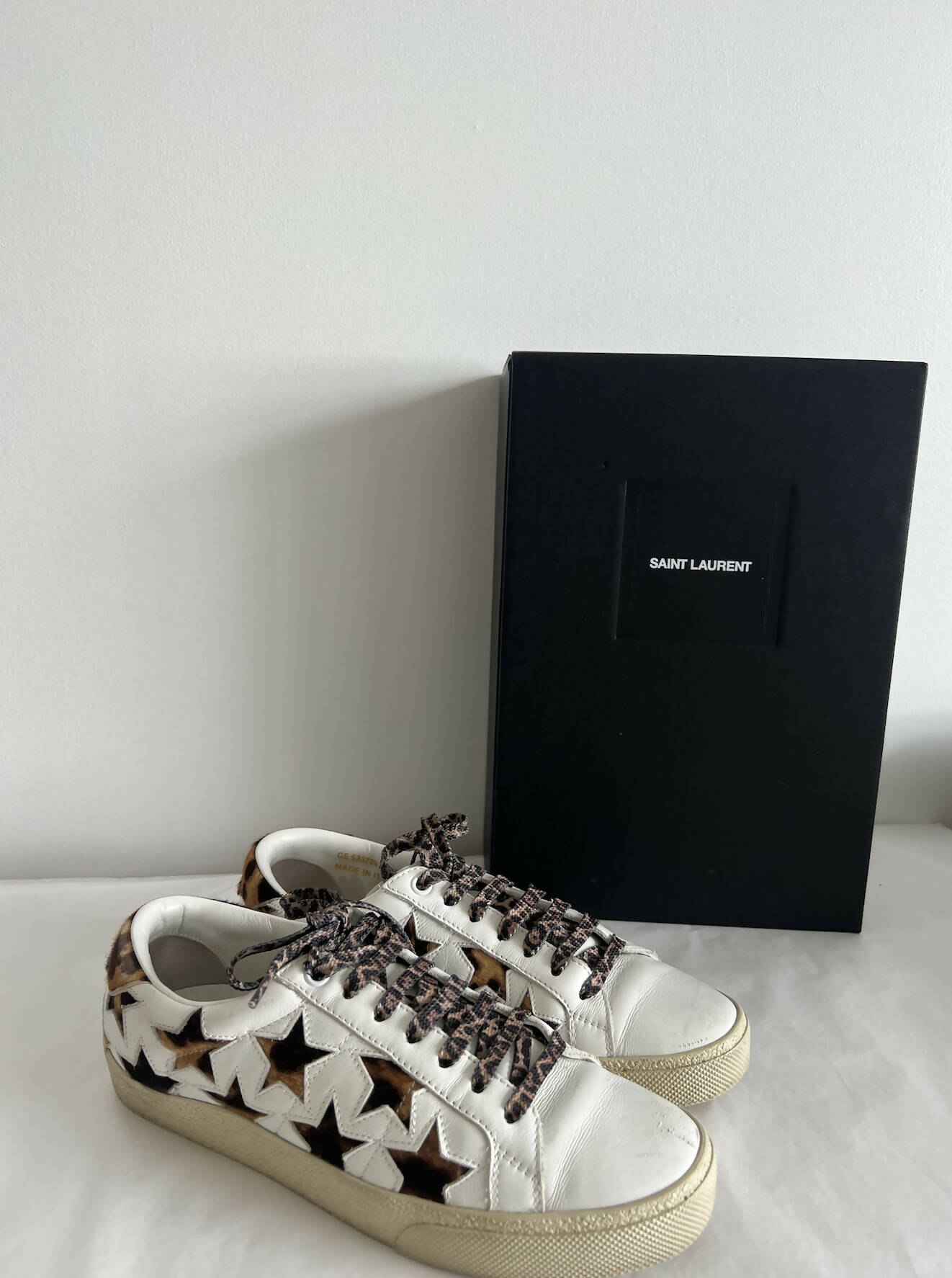 A pair of Saint Laurent Court Classic Sneakers Stars - Leopard/Cheetah by EXCHANGE is displayed beside a black Saint Laurent box against a white background, showcasing chic Auckland style.