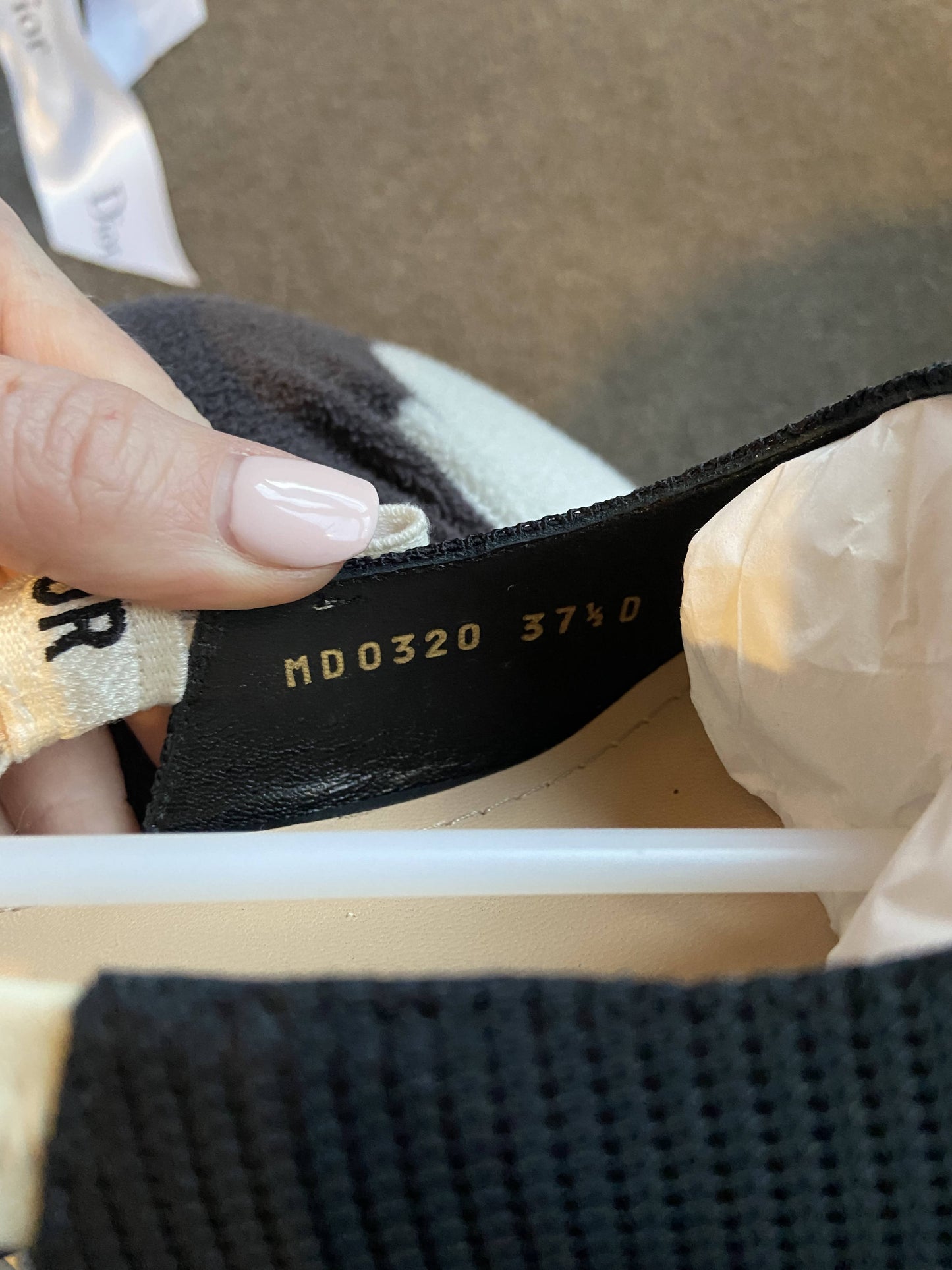 A close-up shows a hand holding the inner lining of a black EXCHANGE Dior J’adior Slingback heel, featuring a gold-printed code MD0320 size 37.5 label and tissue paper stuffed inside.