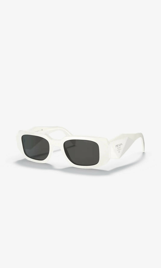 White rectangular EXCHANGE Prada Sunglasses with black lenses and thick white frames, shown on a white background. Small dents and scratches present. Brand name visible on the left temple. Price: $628 NZD.