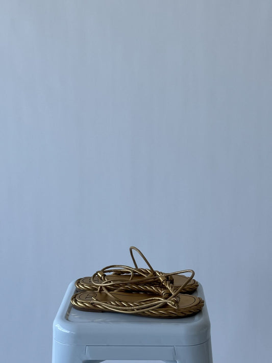 A pair of EXCHANGE Valentino - THE ROPE SANDALS in size 39 rests atop a light blue plastic stool against a plain, light gray background. This sold-out style is celebrated for its elegance and timeless appeal.