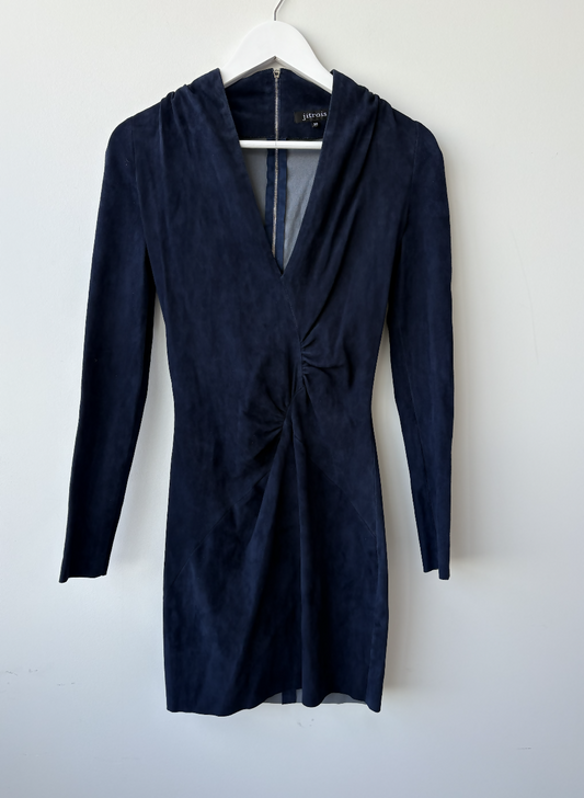 The EXCHANGE STORE Jitrois Navy Velvet Longsleeve Mini Dress, featuring a fitted silhouette and gathered waist, exudes subtle rock-chic vibes as it hangs on a white hanger against a plain light-colored wall.