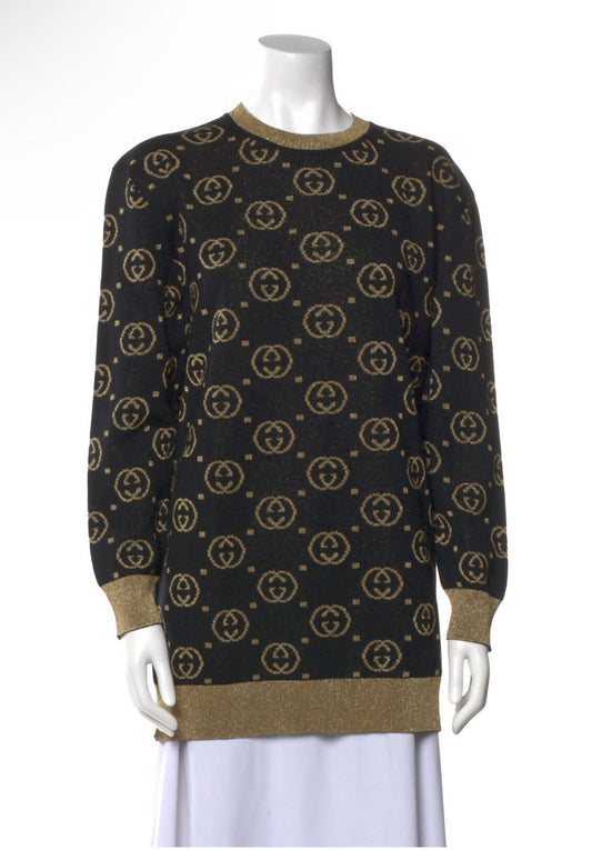A black EXCHANGE Gucci Jacquard Logo Knit Sweater from SS19, with gold jacquard logos and gold trim on the collar, cuffs, and hem, displayed on a white mannequin styled with a white skirt.